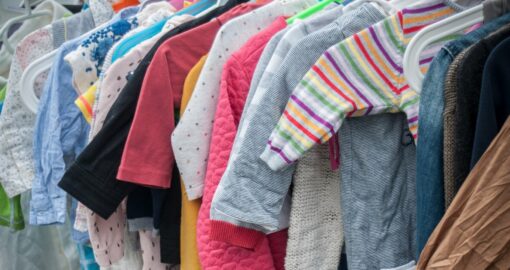 Babykleidung hängt an der Stange auf dem Kinderflohmarkt