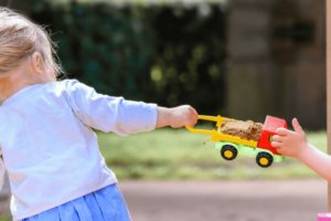 Streit um's Spielzeug: Zwei Kinder streiten sich um einen Spielzeug-Laster