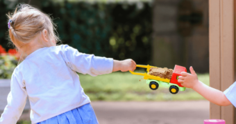 Streit um's Spielzeug: Zwei Kinder streiten sich um einen Spielzeug-Laster