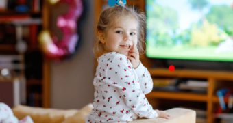 Fröhliches junges Mädchen vor einer Zeichentrickserie: Sind Videos und Fernsehen schädlich für Kinder?