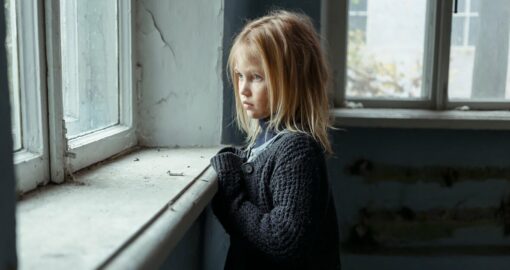 Vernachlässigender Erziehungsstil: Vernachlässigtes Mädchen schaut traurig aus dem Fenster