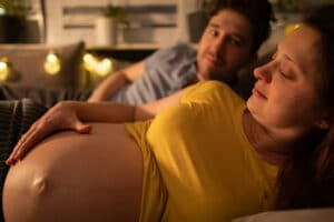 Hochschwangere Frau liegt im Bett - Hat sie einen Blasensprung?