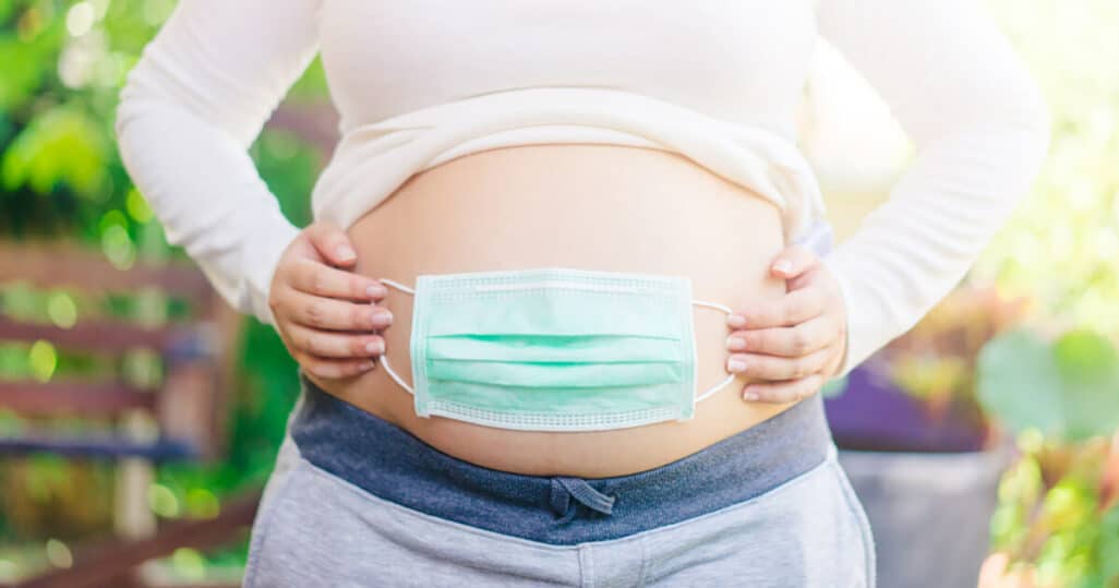 Schwanger in Corona-Pandemie: Schwangere hat Maske über dem Bauch