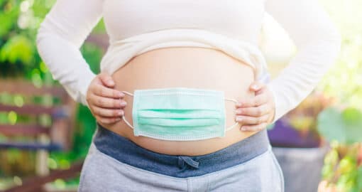 Schwanger in Corona-Pandemie: Schwangere hat Maske über dem Bauch