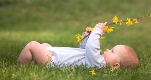 Baby spielt im Frühling mit Blumen