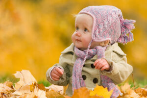 Baby sitzt im Herbst in einem Blätterhaufen