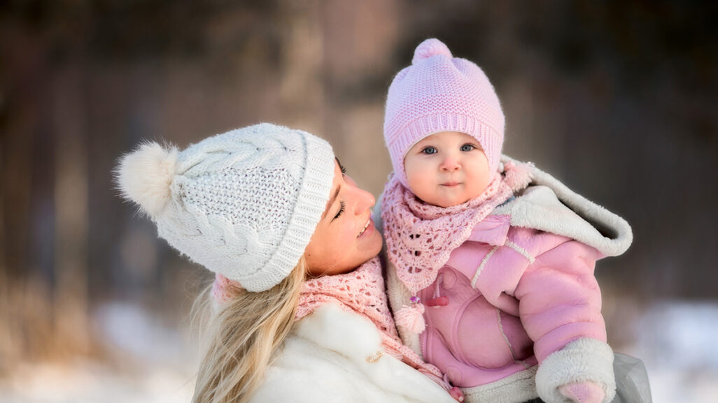Mutter mit Baby im Arm im Winter