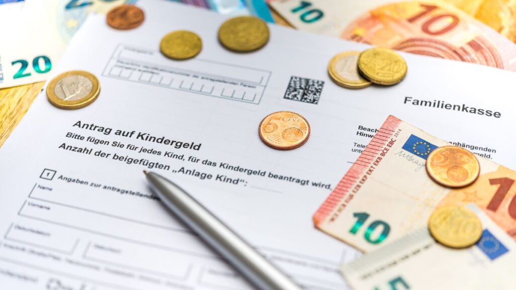 Kindergeldantrag mit Euromünzen, Scheinen und Kugelschreiber