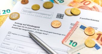 Kindergeldantrag mit Euromünzen, Scheinen und Kugelschreiber