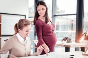 Schwangere Frau bei der Arbeit mit Kollegin
