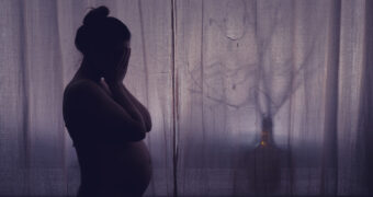 Schwangere mit Tokophobie steht in dunklem Zimmer und kann nicht schlafen